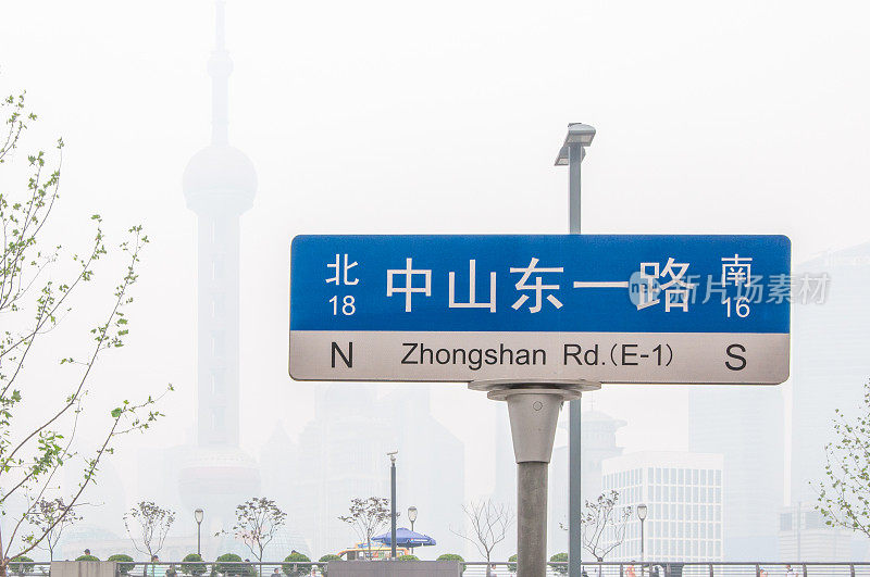 在雾笼罩的上海电视塔的背景下，上海滨水区的街道标志