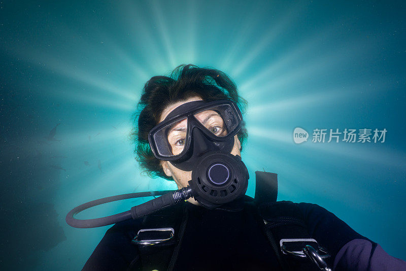 一位成熟的女性戴着太阳光环水下潜水自画像