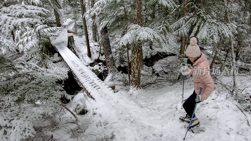 女性徒步旅行者接近积雪覆盖的木板路