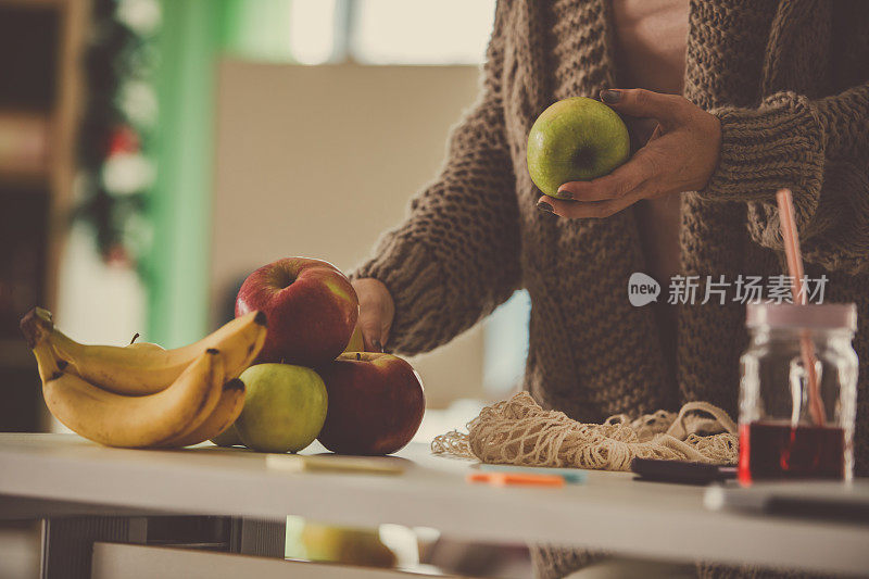 女人从可重复使用的购物袋中取出水果