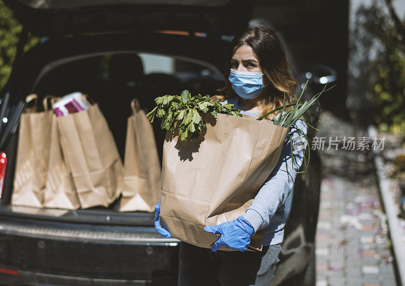 买菜回家的女人。戴上防护口罩和手套