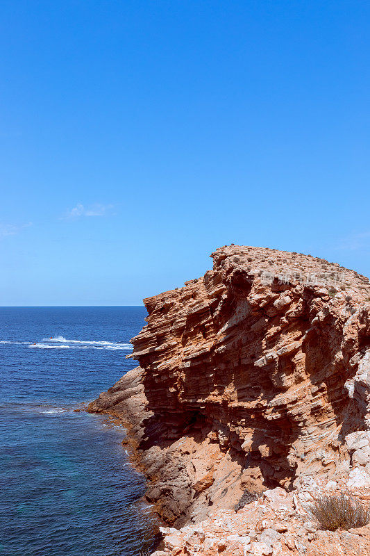 蓬Galera角。西班牙巴利阿里群岛的伊比沙岛。在碧绿的大海里，一个冻结在石头里的波浪。