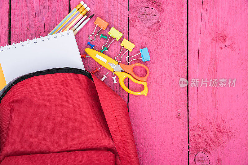 顶视图红色书包为教育儿童的粉色木制背景回到学校的概念