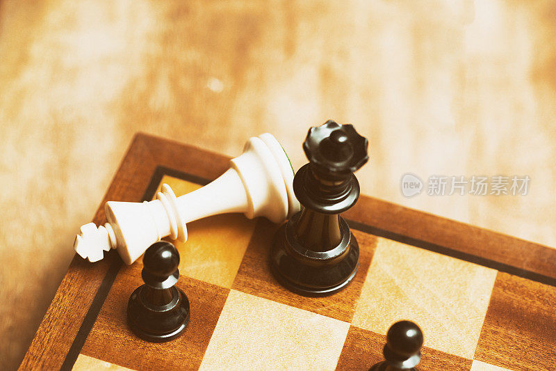 倒下的国际象棋白国王在黑皇后的脚下