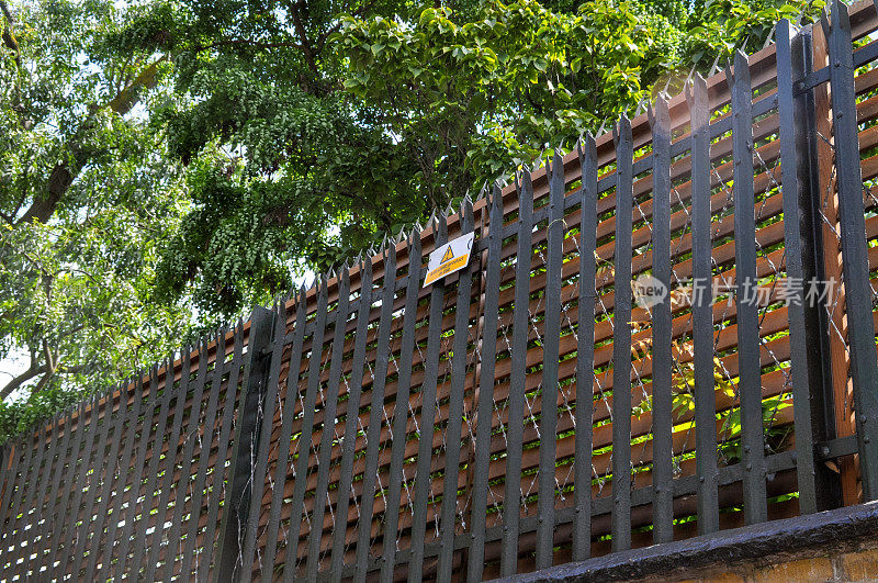 在私人住宅的金属围栏上的一个标牌上写着“正在使用的防攀爬产品”