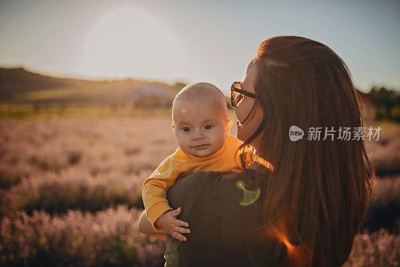 快乐的妈妈抱着她可爱的儿子在薰衣草地里