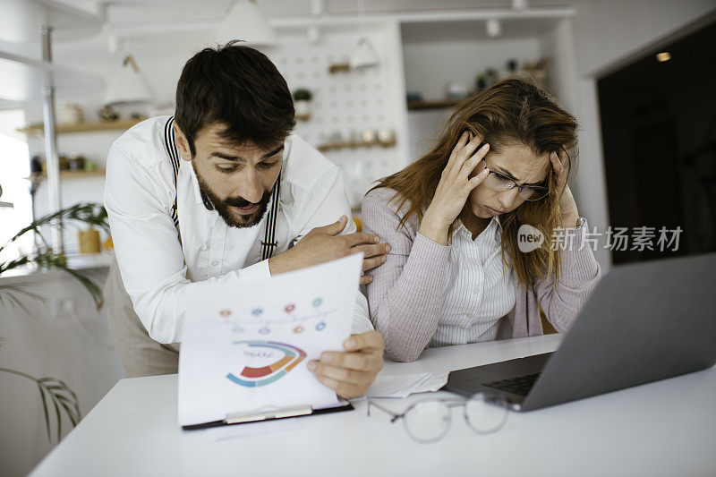 一对沮丧的夫妇在家里用笔记本电脑上的库存照片查看账单