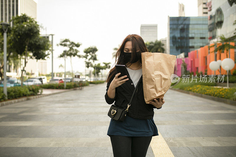 亚洲女性在街上走路时使用手机