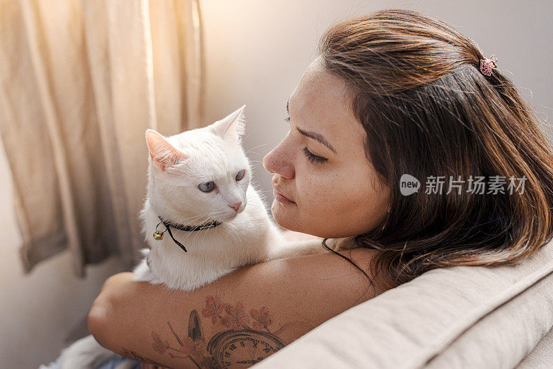 一个女人在沙发上和他们的猫一起看电视