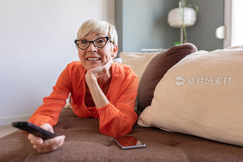 年长的女人在家里的沙发上休息看电视