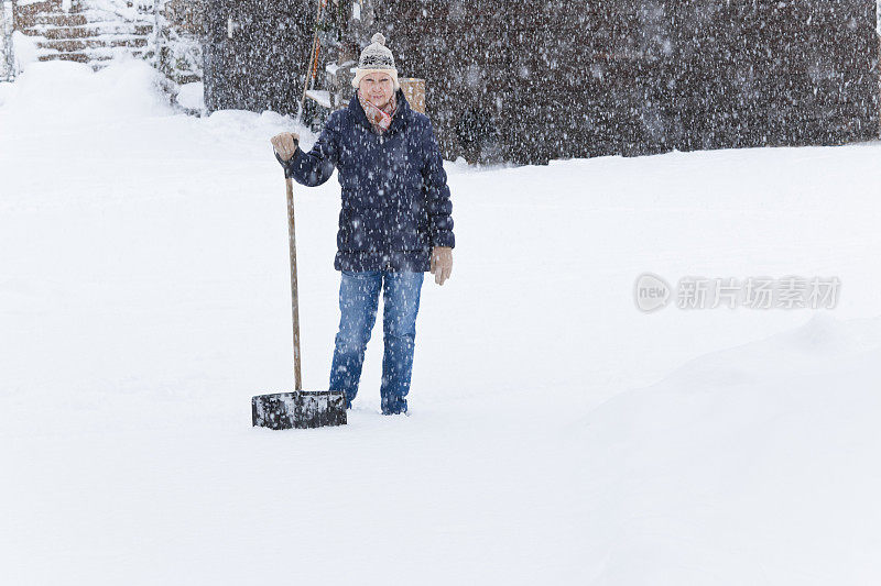 美丽的女人在大雪中拿着雪铲