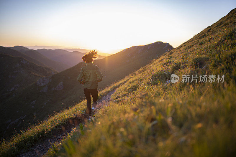 一个健康的女人在日落时分在山上慢跑。