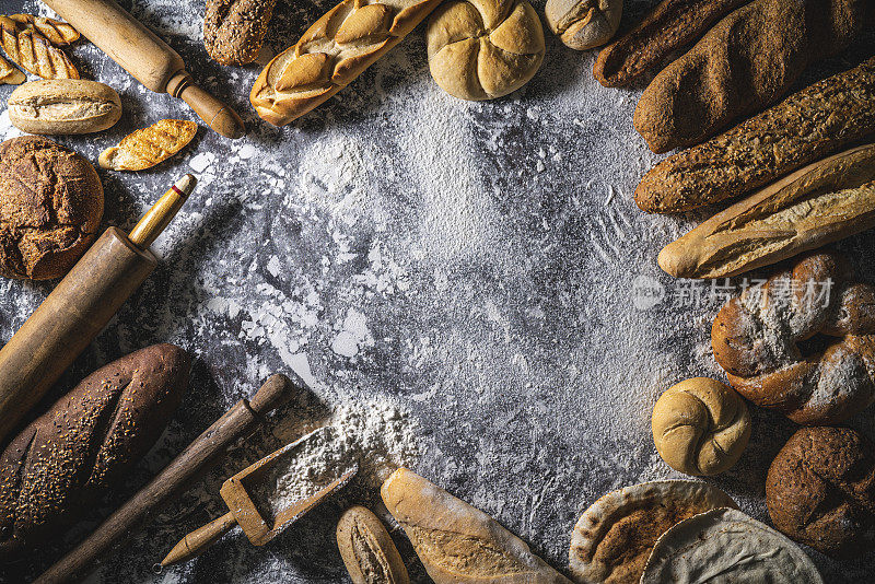 面包框架与复制空间的面粉背景与擀面杖和各种面包面包和小圆面包