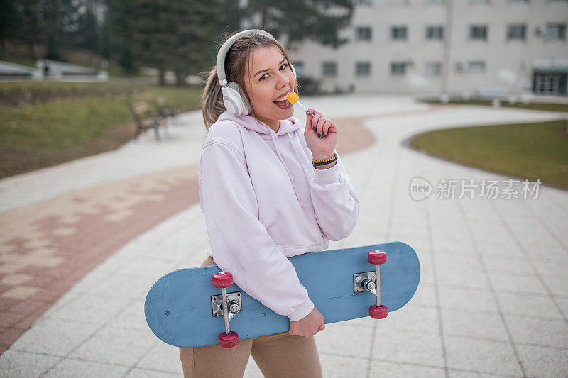 戴着耳机，舔着棒棒糖，拿着滑板的美女