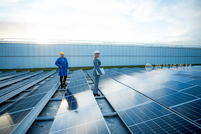 一名女性经理工程师在太阳能电池板工地与一名男性技术员在一起