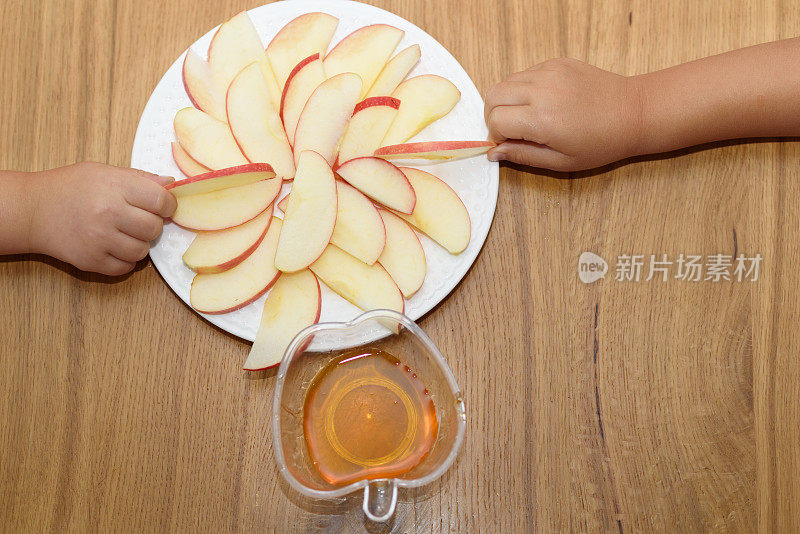 俯视图苹果片放在木桌上的白色盘子上。孩子们手里拿着苹果片