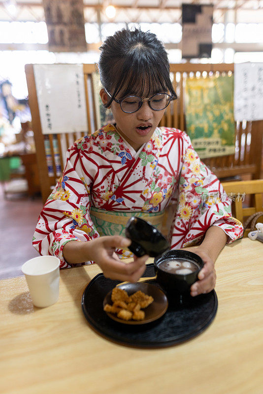 穿着和服的少女在日本餐馆吃白玉真哉红豆汤