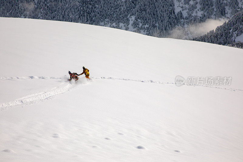 两个滑雪板运动员一起在刚下过的雪地上滑行