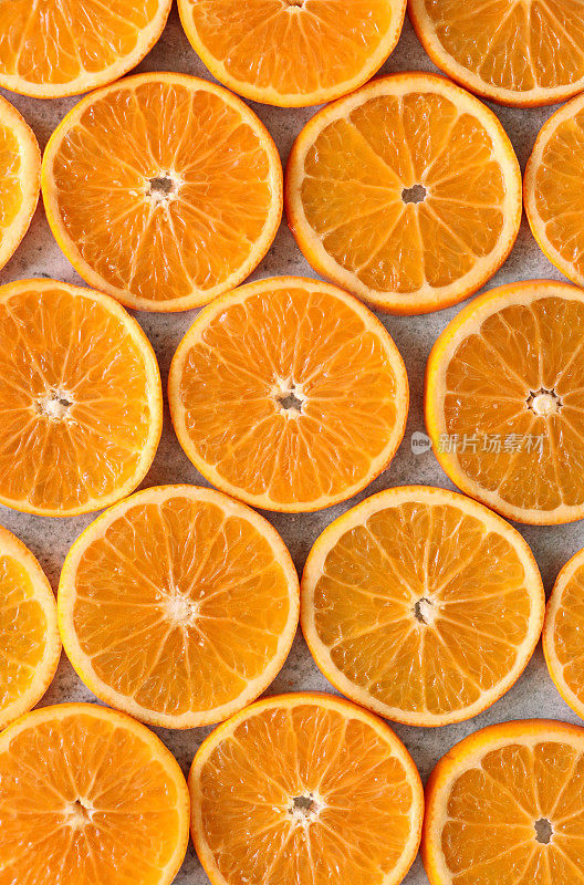 全帧图像一排排柑橘水果切片，截面塞维利亚橙子，斑驳的灰色背景，提高的观点