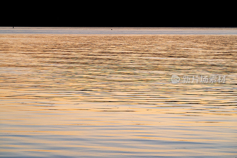 夕阳映照在广阔的海面和遥远的海岸线上