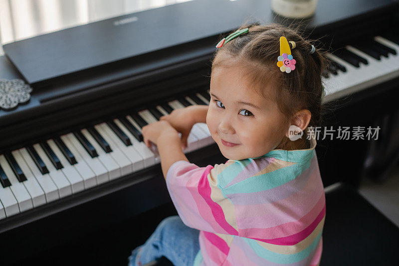 亚洲小女孩弹钢琴很开心。