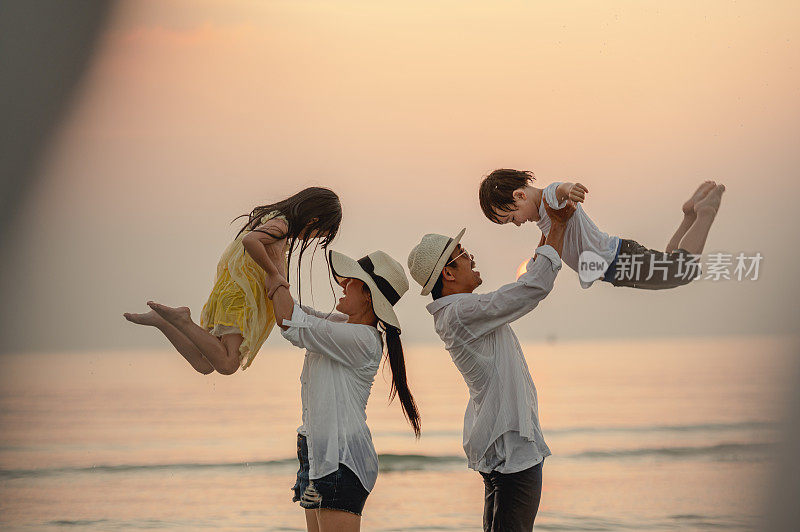 快乐的亚洲家庭在日落的海滩上玩海。全家人都喜欢带着孩子在海滩上玩耍。家庭、旅行、生活方式、度假概念。