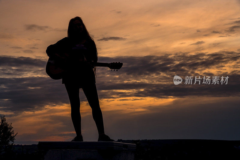 剪影女子在日落弹吉他