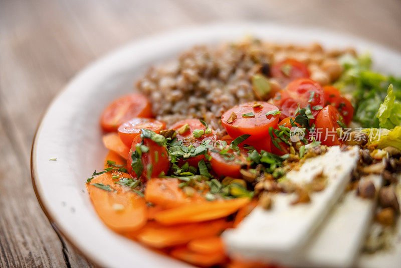 一个平衡和丰富多彩的健康沙拉，混合蔬菜，奶酪，鹰嘴豆和荞麦