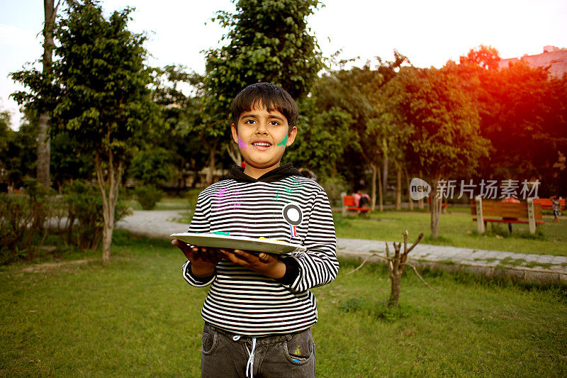 6-7岁的男孩在Holi节上用手打彩色粉盘