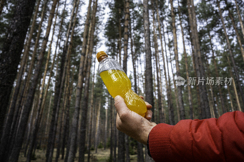 在森林里手持运动饮料瓶。