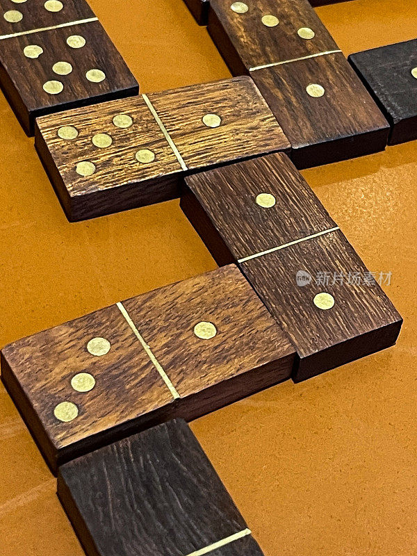 图像的木制多米诺骨牌游戏在橙色的桌子，分支路径和匹配的数字在著名的，流行的棋盘游戏，高架视图