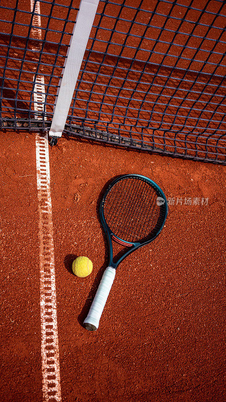 网球拍和球在红土场上仍是高空垂直网球