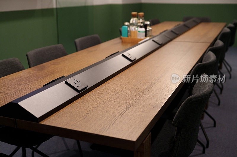 现代化会议室的内部景观，配备了方便的电源插头，舒适的办公椅和各种办公用品的原始硬木桌子。