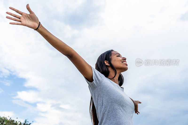 年轻女子在户外张开双臂放松