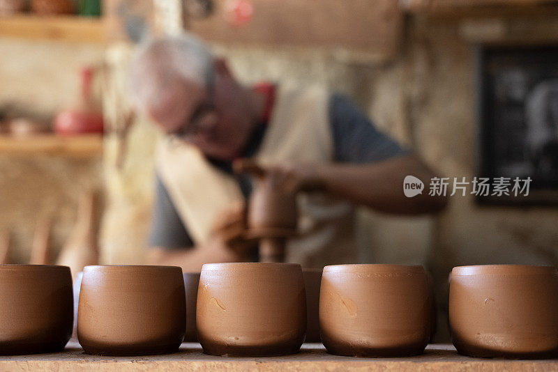 一位老人正在制作一个陶杯