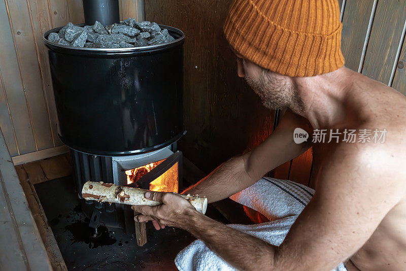 一个年轻人在一个漂浮的桑拿浴室里放松，他打开了烧木头的炉子