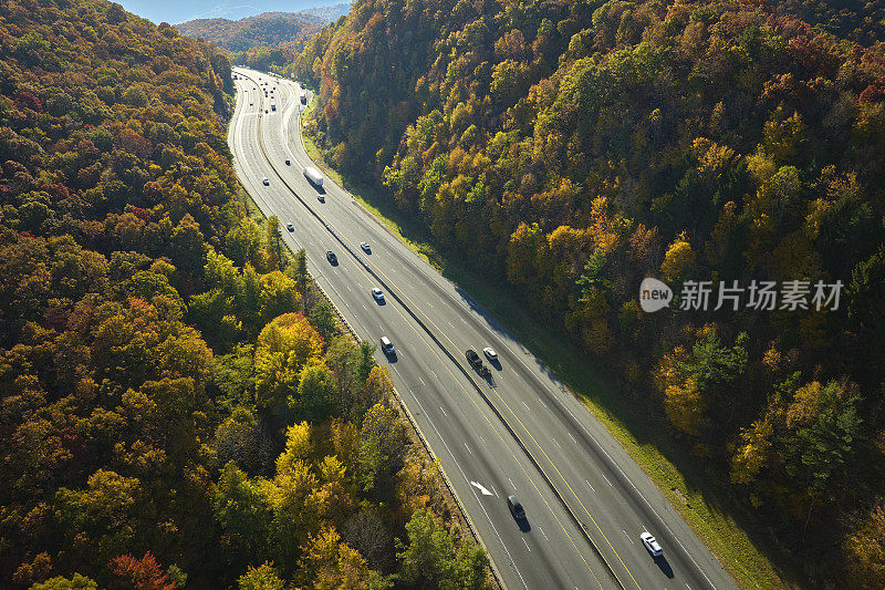 通往北卡罗来纳州阿什维尔的I-40高速公路穿过阿巴拉契亚山脉，那里有黄色的秋天森林和快速移动的卡车和汽车。高速州际交通的概念