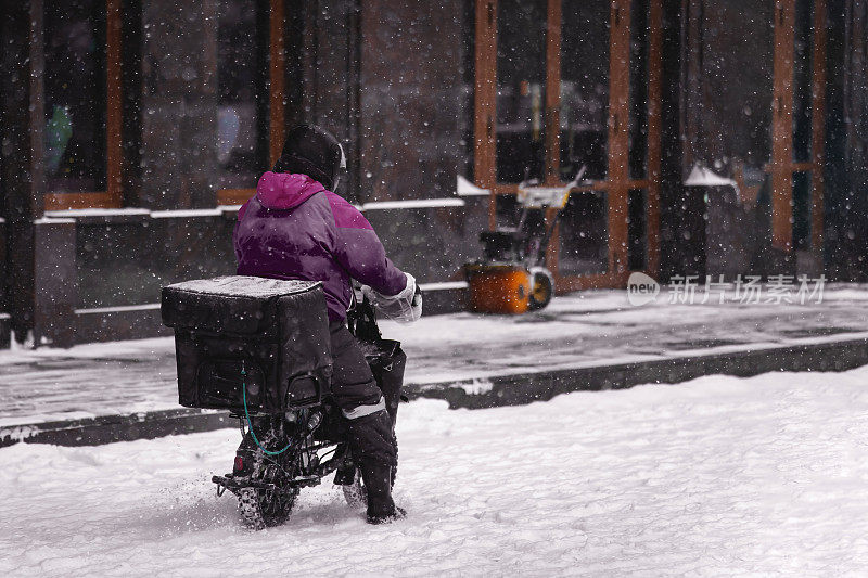 一名快递员骑着电动摩托车在雪地里骑行