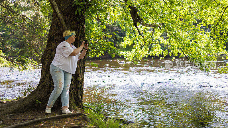 成熟的游客在宾州波科诺斯的河岸上拍摄夏天的大自然