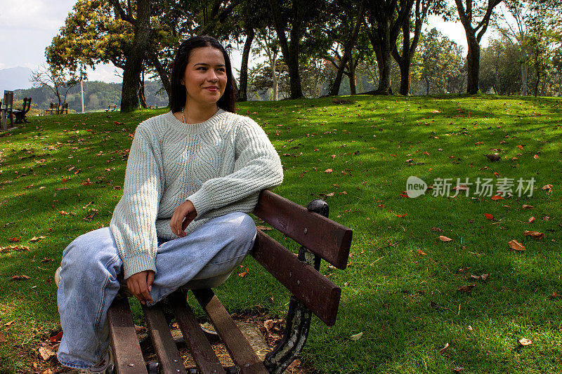 漂亮的年轻女子坐在木凳上，望着别处