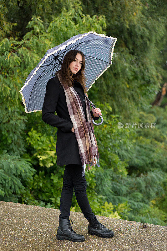 女人撑着伞在秋雨中