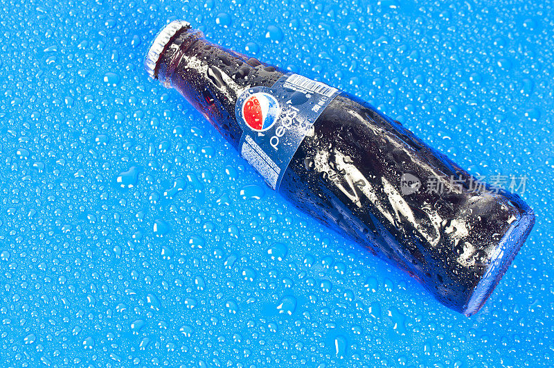 百事可乐瓶在蓝色和潮湿的表面