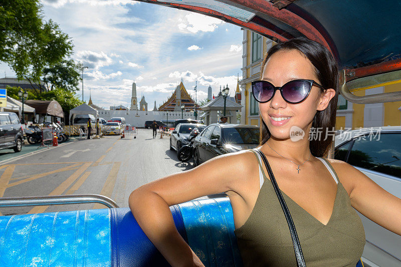 年轻美丽的多民族女游客的肖像骑在嘟嘟，而探索曼谷的城市泰国