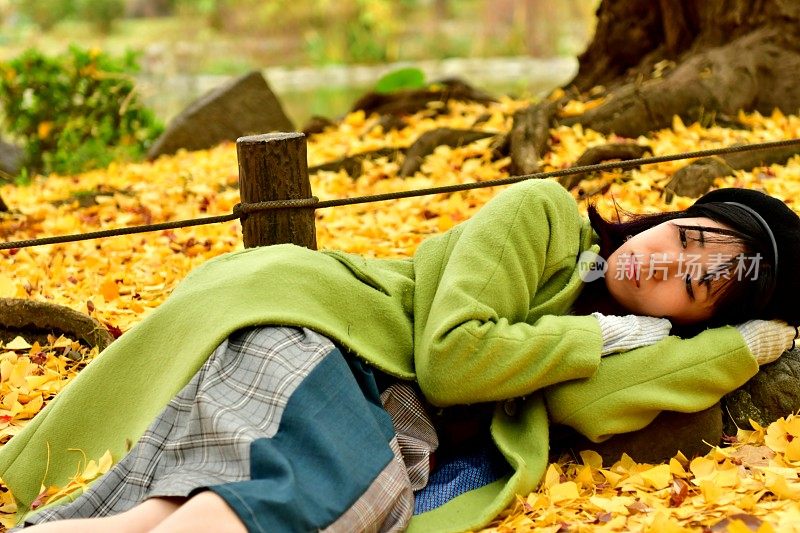 日本女人在秋天的银杏树下休息