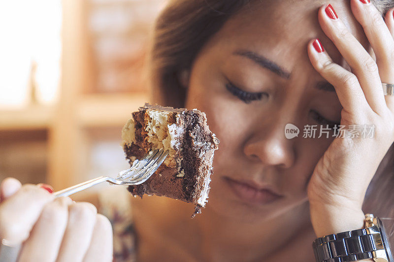 抑郁的女人头痛，安慰自己，吃蛋糕