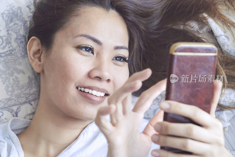 一个在床上玩手机的亚洲女人