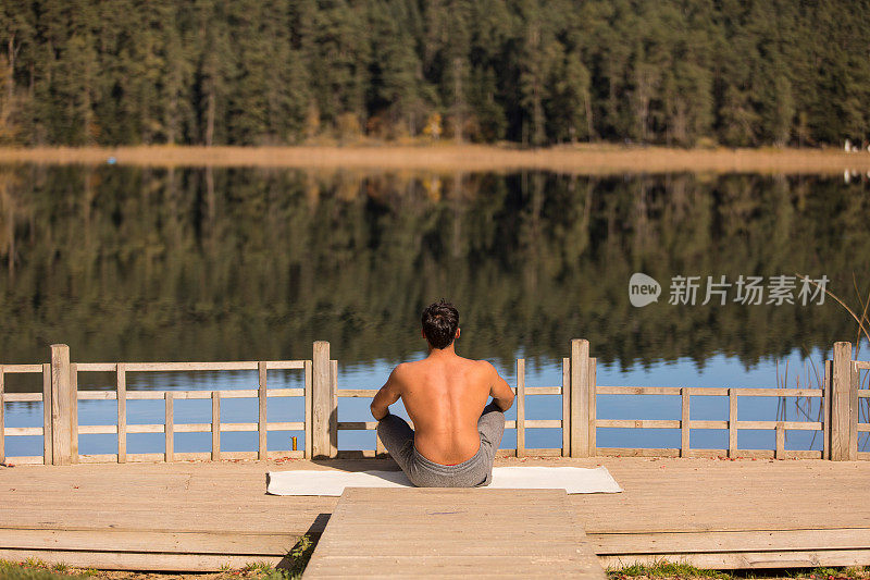 年轻人在大自然中做瑜伽锻炼，在湖边