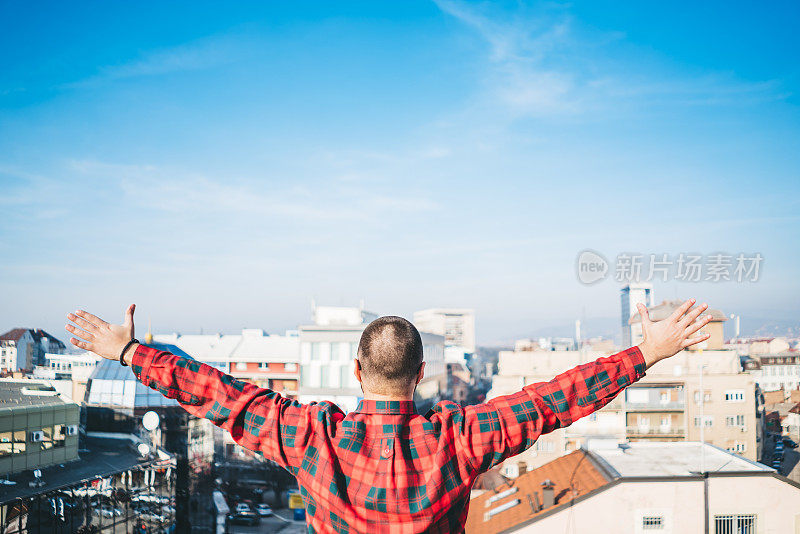 男人在屋顶上张开双臂