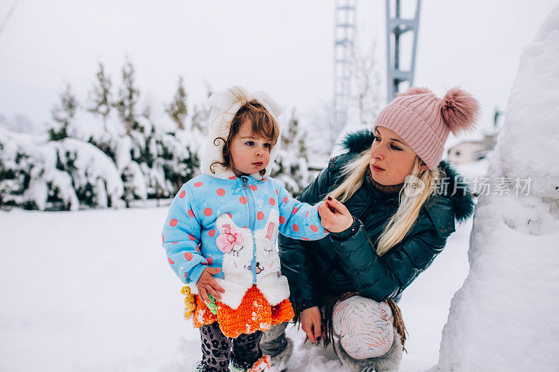 快乐的妈妈喜欢和她的孩子在雪地里玩