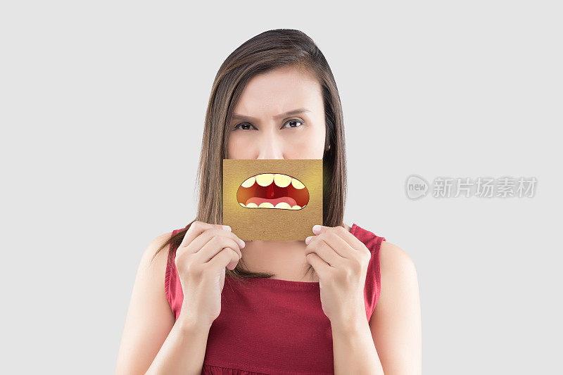 亚洲妇女在红色衬衫拿着棕色纸与黄色的牙齿卡通图片他的嘴在灰色的背景，口臭或口臭，与保健牙龈和牙齿的概念
